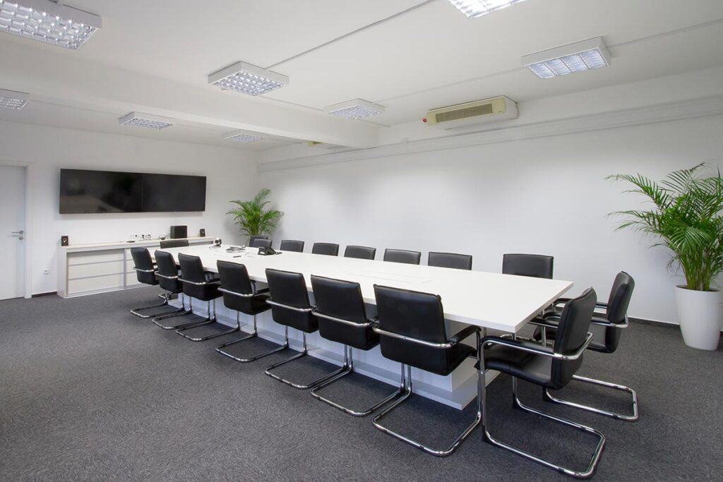 Spacious conference room with modern furniture and presentation screen.